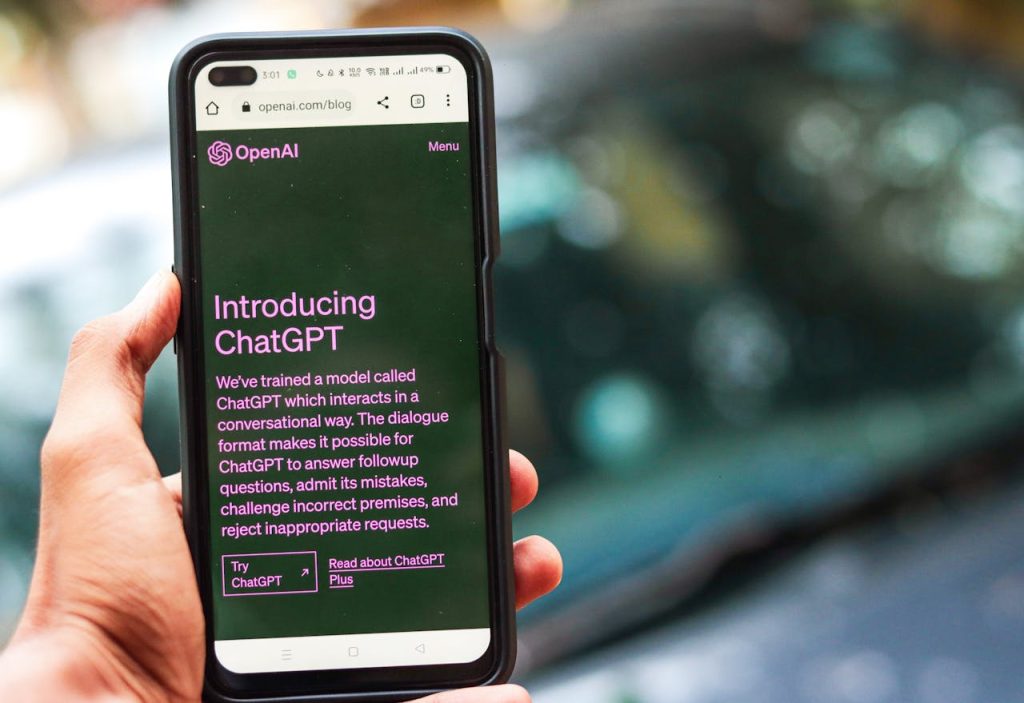 Home Close-up of a smartphone showing ChatGPT details on the OpenAI website, held by a person.